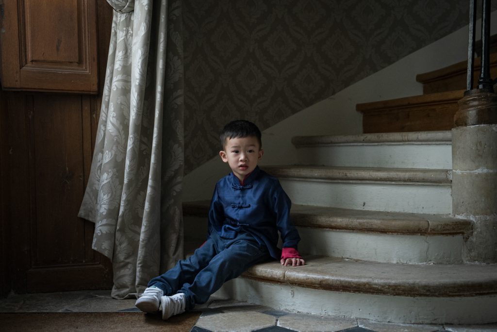 Petit garçon en tenue bleue traditionnelle assis sur les marches d'un escalier ancien
