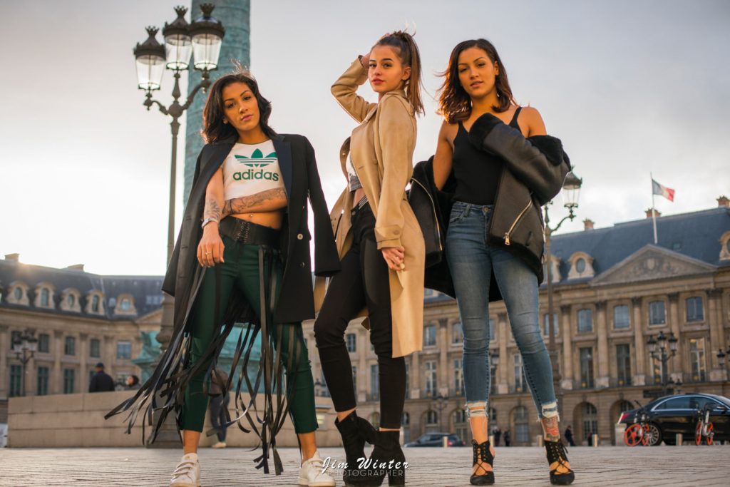 Trois jeunes femmes posant en tenues streetwear sur la place Vendôme à Paris