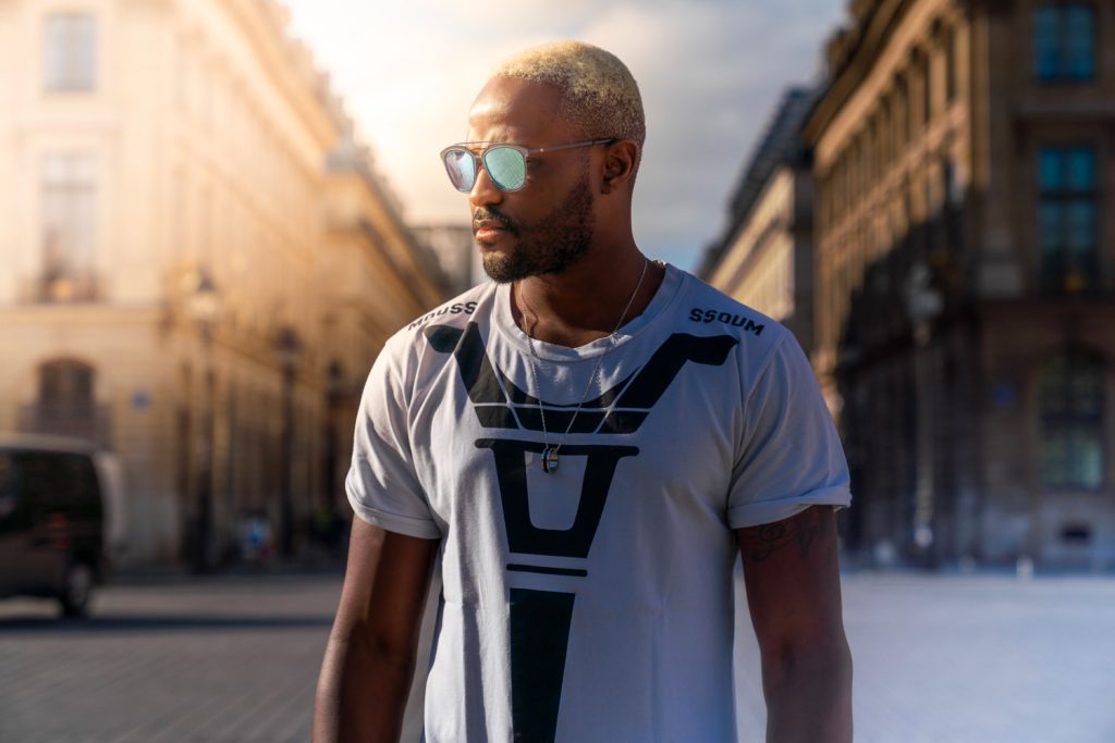 Homme en lunettes de soleil et tee-shirt blanc dans une rue parisienne au soleil couchant